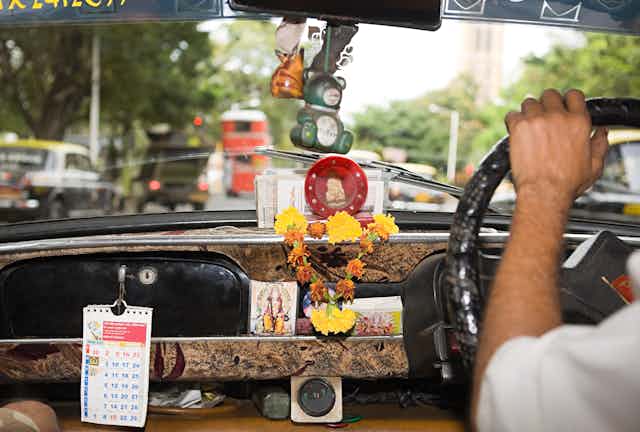 Inside of a taxi showing various sacred objects.