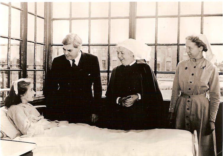 People standing over a patient in a hospital bed