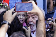 An ageing man poses for a photo with a young child.