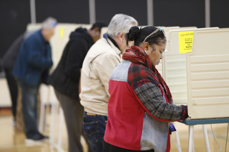 People stand at voting stations casting their vote.