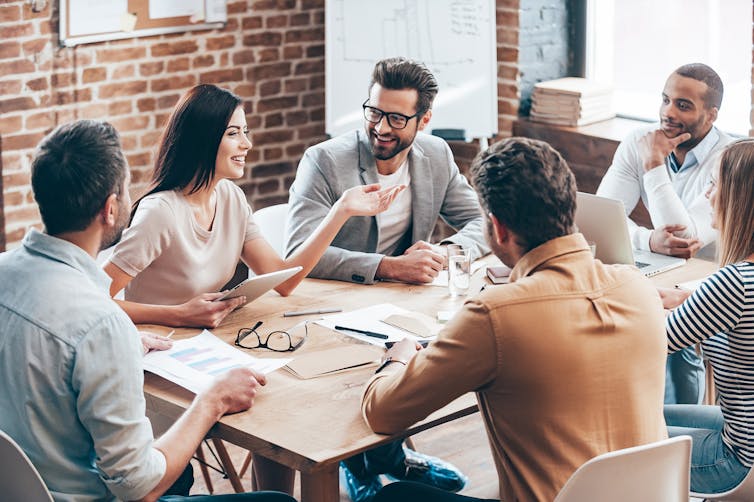 A group of people sitting around a table and talking
