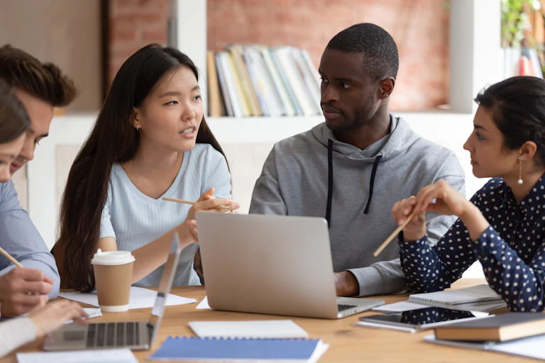 People sitting together at a desk talking.