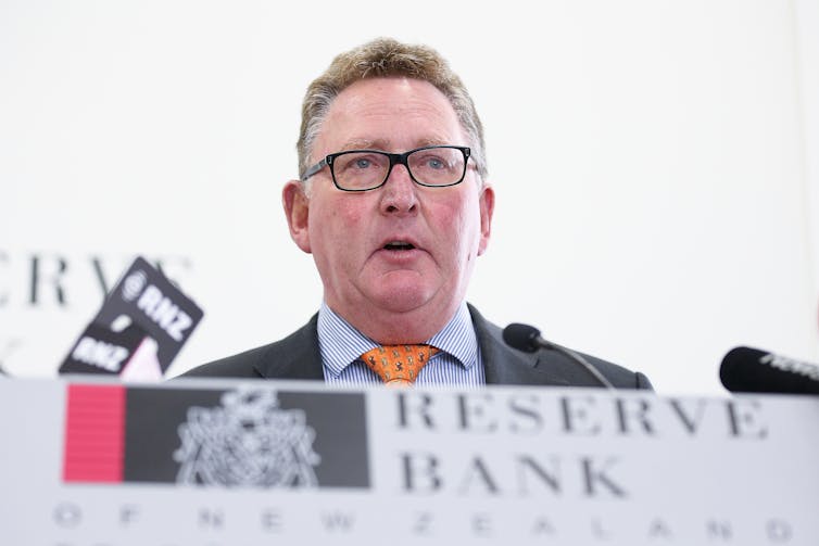 Adrian Orr in front of microphones and Reserve Bank sign