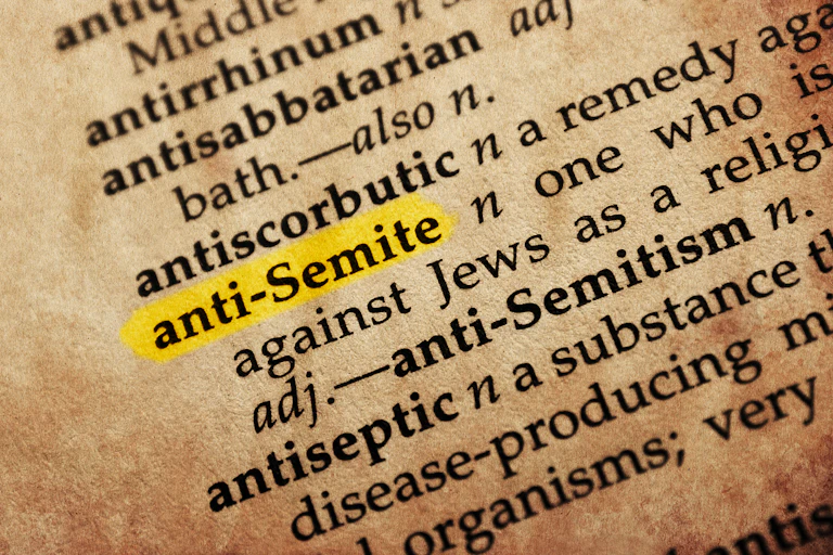 An old, yellowed dictionary page shows entries that begin with the letters 'ant,' including the word "anti-Semite,' which is highlighted.