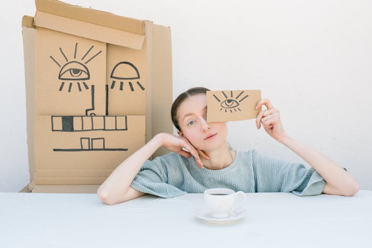 A woman covers her eye with a cardboard piece.