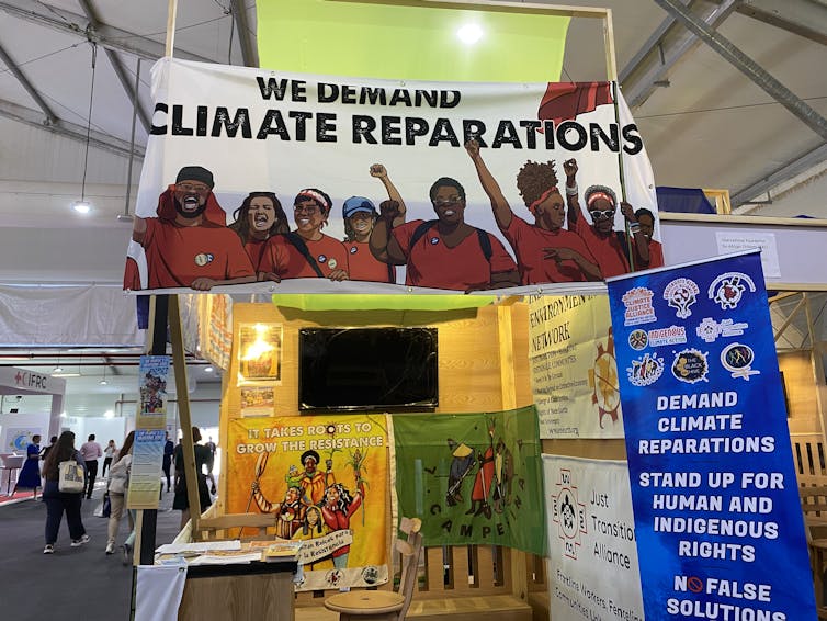 A stall with banners demanding climate reparations.