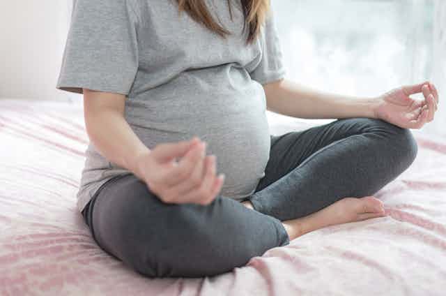 pregnant person sits crosslegged