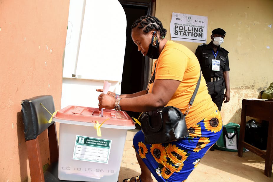 A woman about to cast her vote while a police man observes
