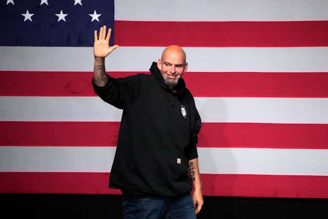 Man waves in front of large US flag