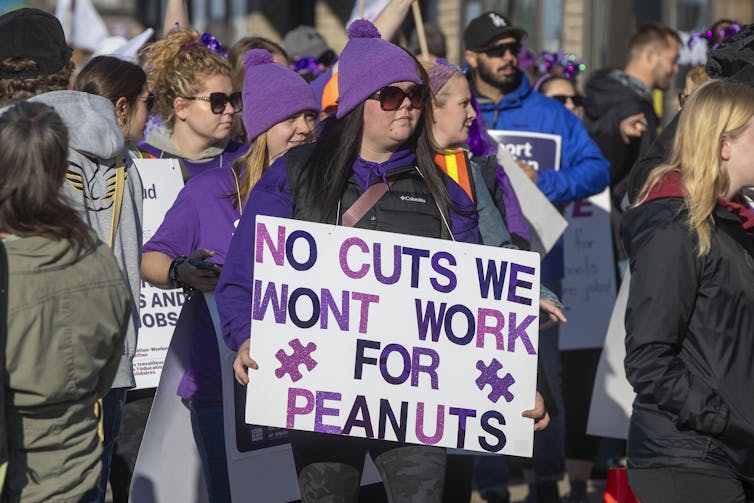 A person with a sign that says 'we won't work for peanuts.'