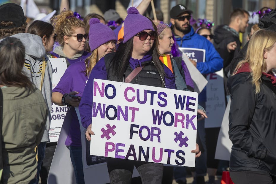 A person with a sign that says 'we won't work for peanuts.'
