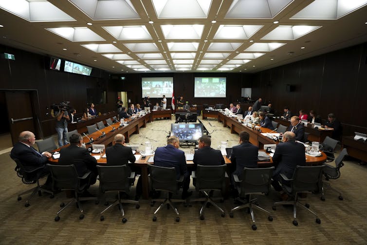 official looking people sit around a conference table discussing abuse in sports culture