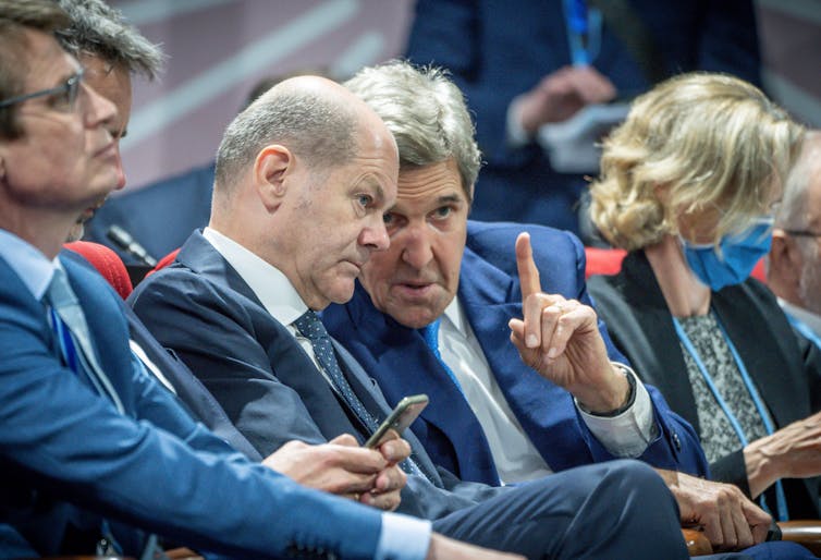Kerry leans toward Scholz and raises a finger as if to point while seated during the UN climate conference.