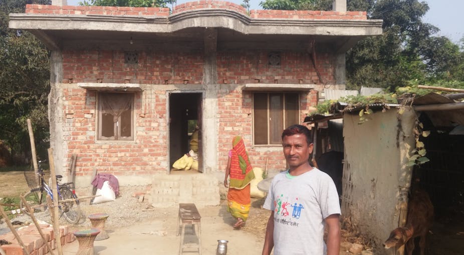 Homme devant une maison en briques, au Népal
