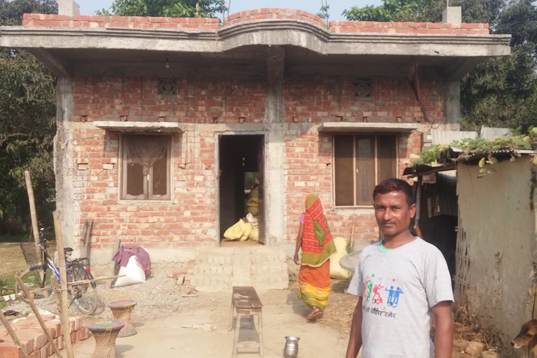 Homme devant une maison en briques, au Népal