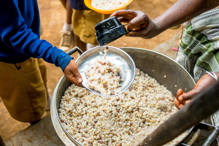 Hands of woman serving a child samp and beans.