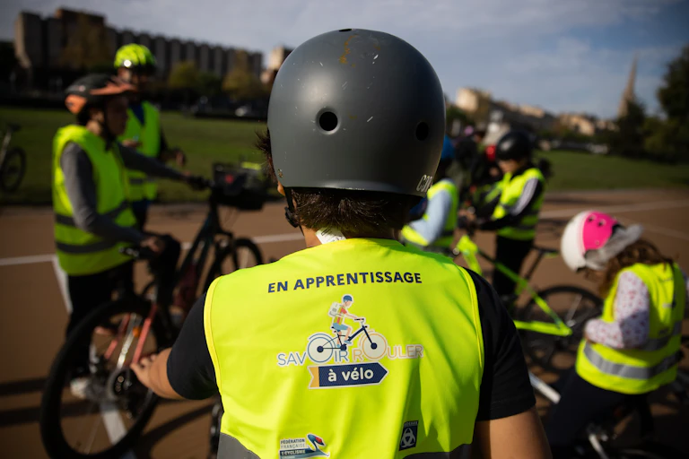 Un écolier portant un casque et un gilet fluo lors d'un cours pour apprendre à se déplacer à vélo en ville