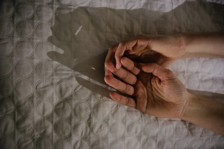 A stock illustration of two male hands touching intimately on a bed.