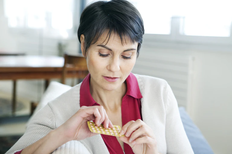 A middle-aged woman holds a blister pack of pills.