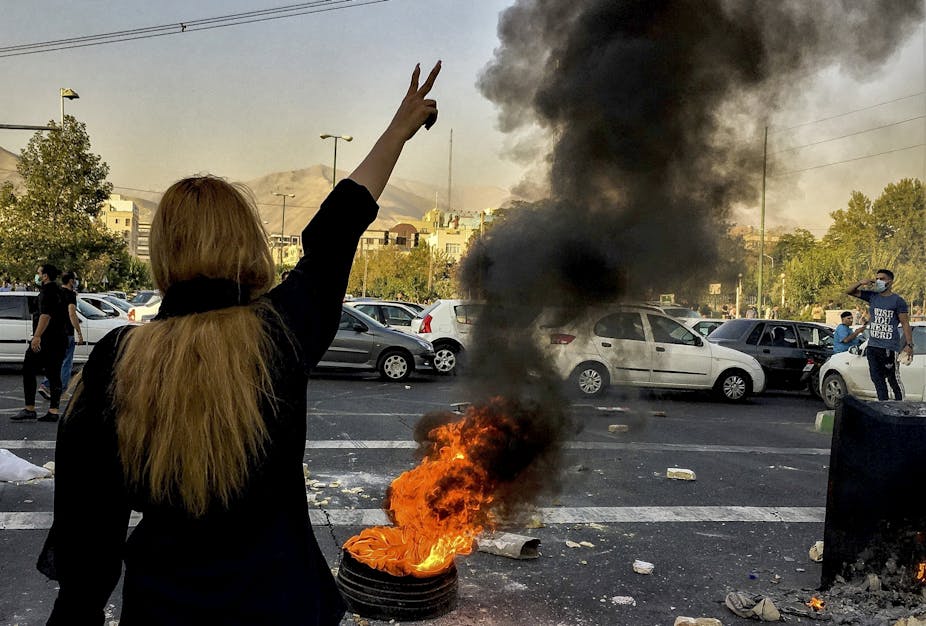 An unveiled woman, with her back to the camera, points two fingers as a sign of victory, during the protests in Iran.
