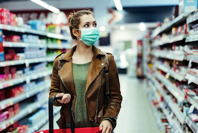 femme dans une allée de supermarché qui porte un masque