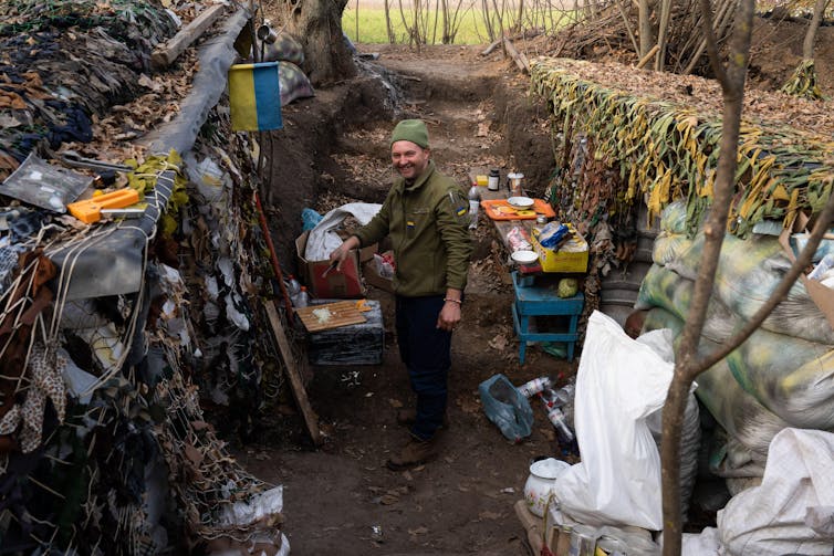 A Ukrainian soldier smiles as he prepares some food in a trench on the front line outside Kherson.