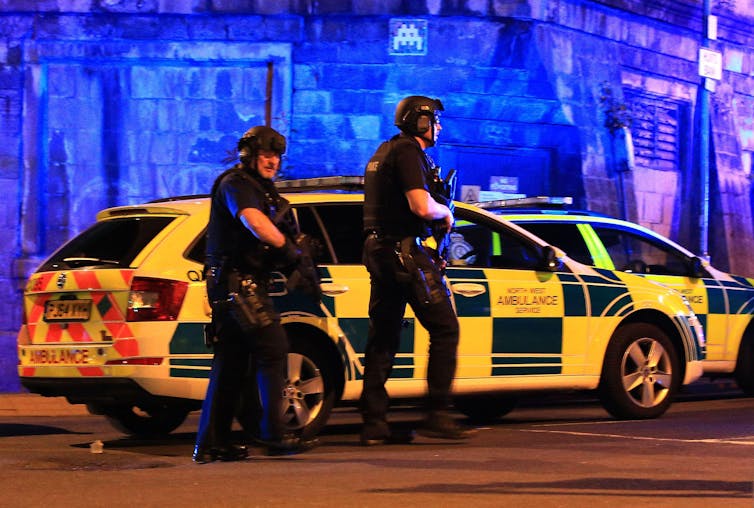 Two armed officers, alongside an ambulance service vehicle, arrive to Manchester Arena after the reported explosion.