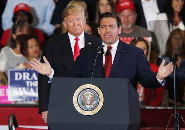 Donald Trump stands behind Republican politician Ron DeSantis at a rally in his campaign for governbor of Florida in 2018