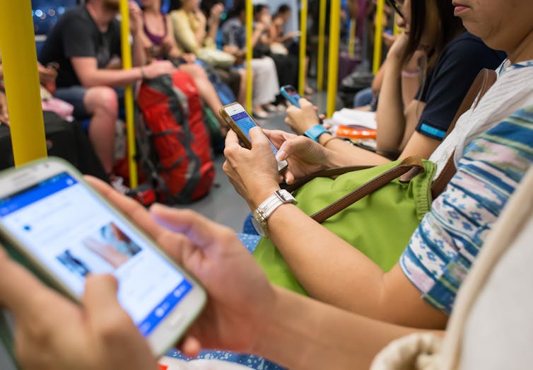 Vue du métro où beaucoup de passagers sont sur leur tablette, téléphone, etc