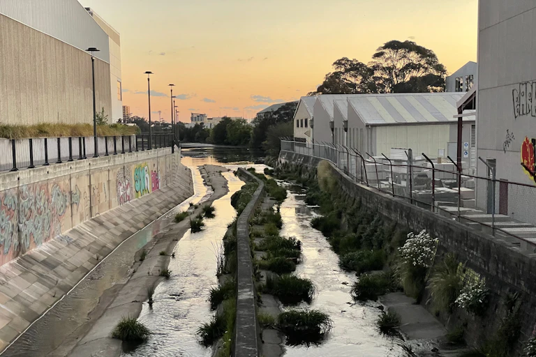a concrete-lined water course runs between old industrial buildings