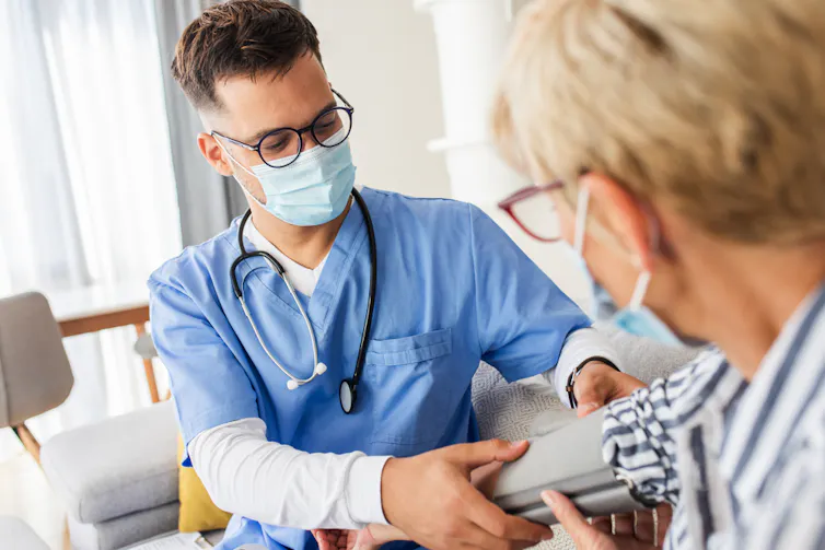 Male nurse wearing mask taking blood pressure of female patient wearing mask