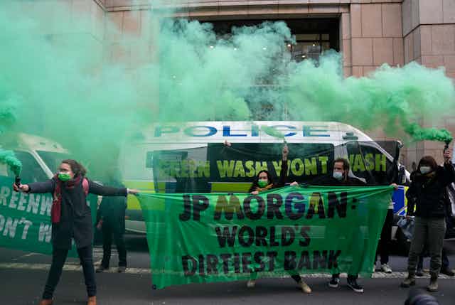 protesters hold signs and stand in green smoke