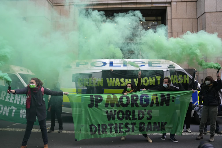 protesters hold signs and stand in green smoke