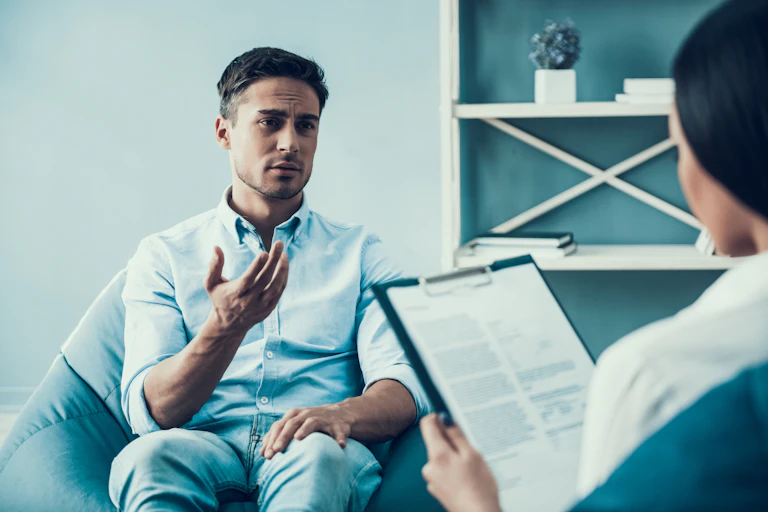 A young man speaks with a therapist.