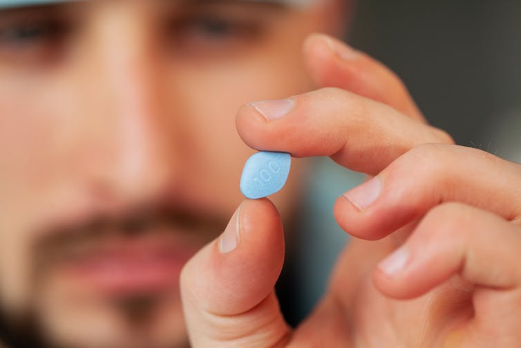 A man holds a viagra pill between his fingers.
