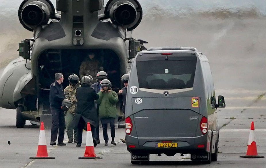 Suella Braverman and others wearing helmets in front of a military Chinook helicopter on a tarmac