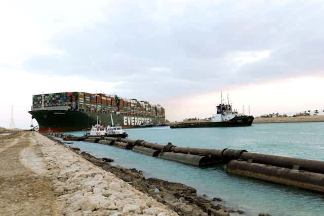 A large container ship with smaller tug boats.