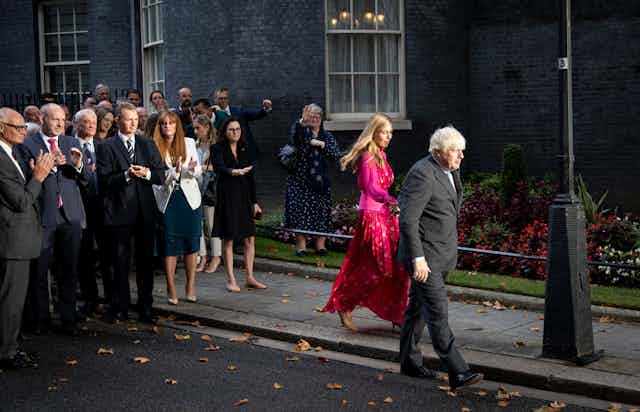 Boris Johnson and his wife, Carrie Johnson, leave Downing Street for the last time as Conservative MPs applaud from behind.