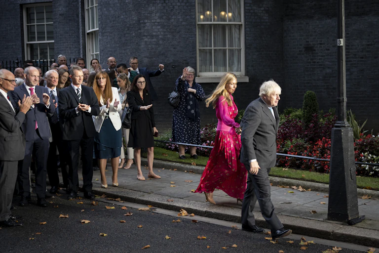 Boris Johnson and his wife, Carrie Johnson, leave Downing Street for the last time as Conservative MPs applaud from behind.