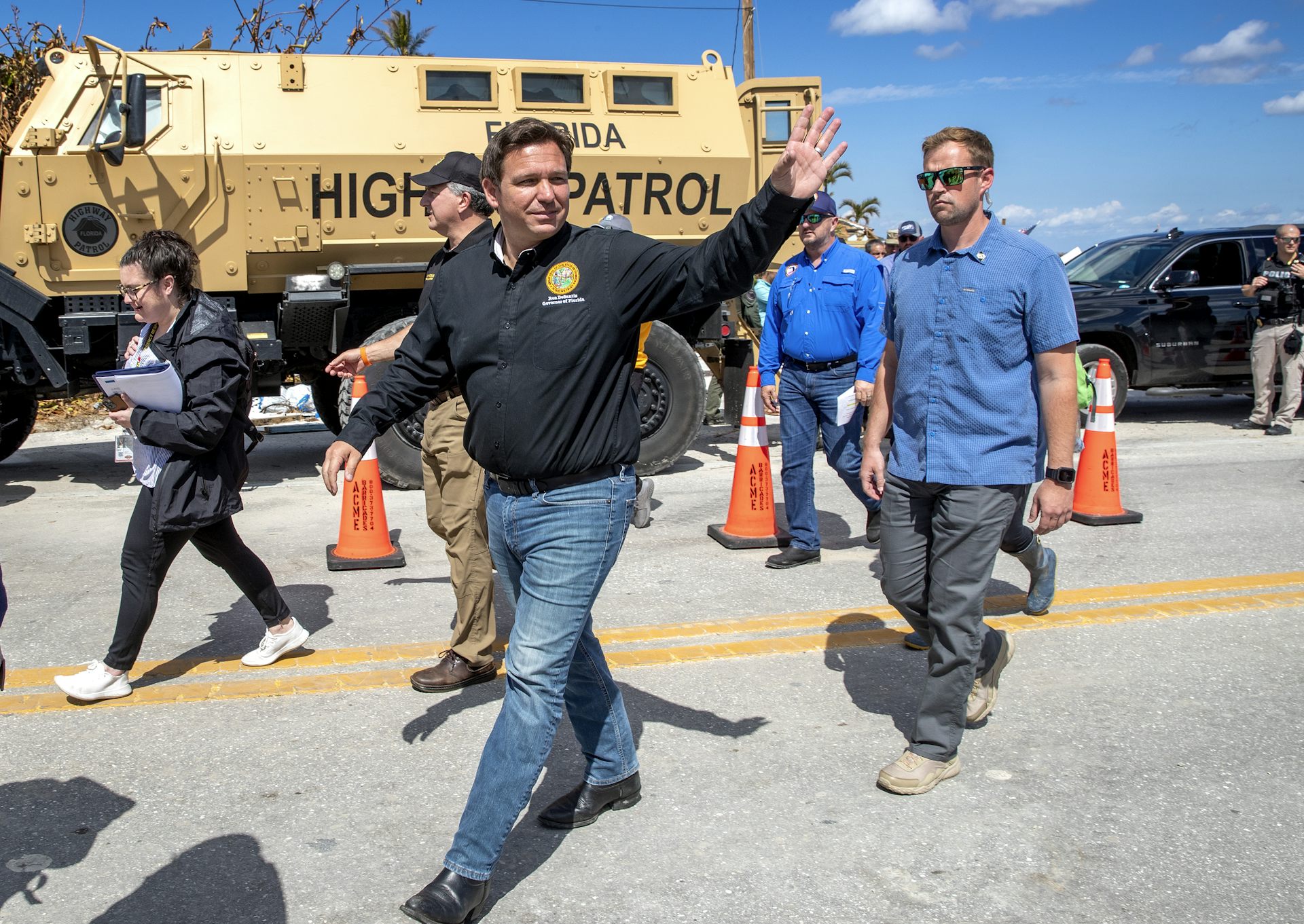 Man waves as he walks past military vehicle