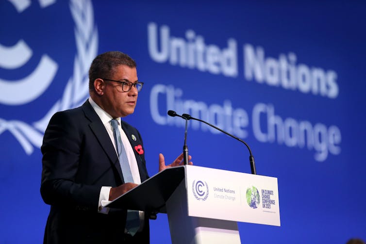Alok Sharma speaks at a podium in front of a blue wall that says United Nations Climate Change.