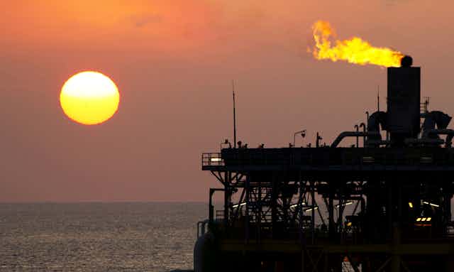 Gas flares from an offshore gas platform at dusk.