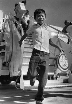 A young boy smiles as he exits an airplane.