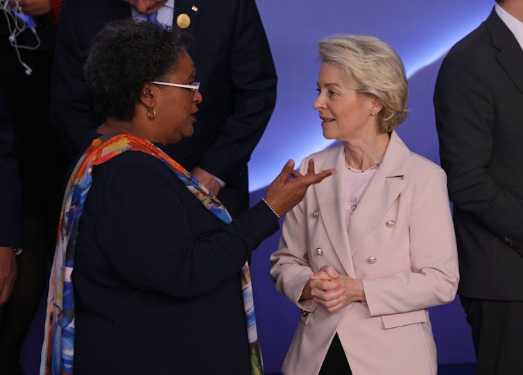 En una sala de reuniones, Mia Motley habla y gesticula mientras Ursula von der Leyen escucha atentamente.