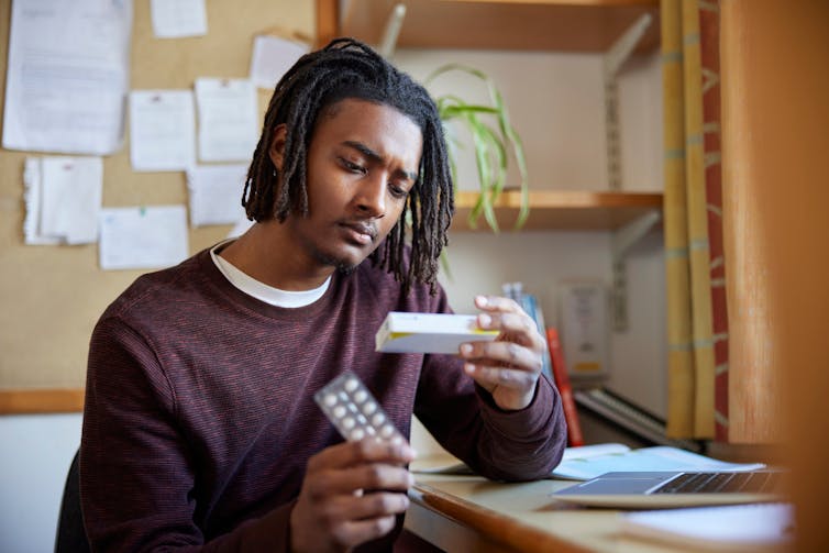 A person sits at a desk looking at a box of tablets.