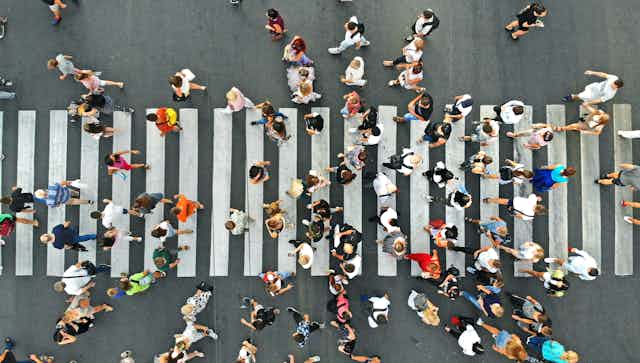 overhead view of a crowd of people walking across a zebra crossing on a street