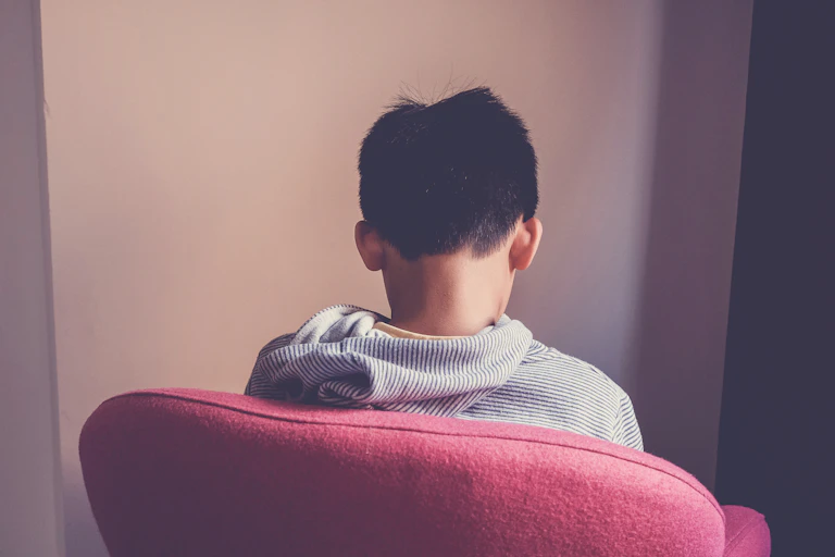 Boy sat in chair facing wall