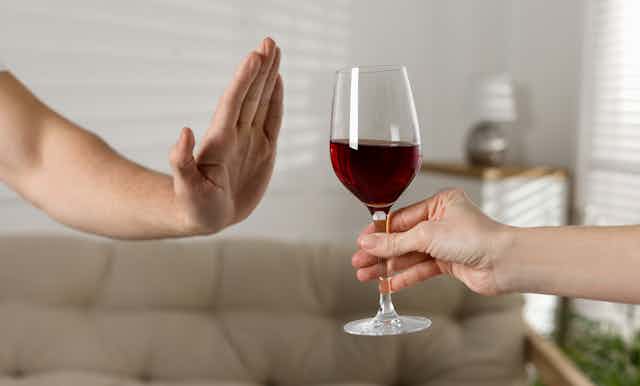 Una mano rechaza una copa de vino tinto