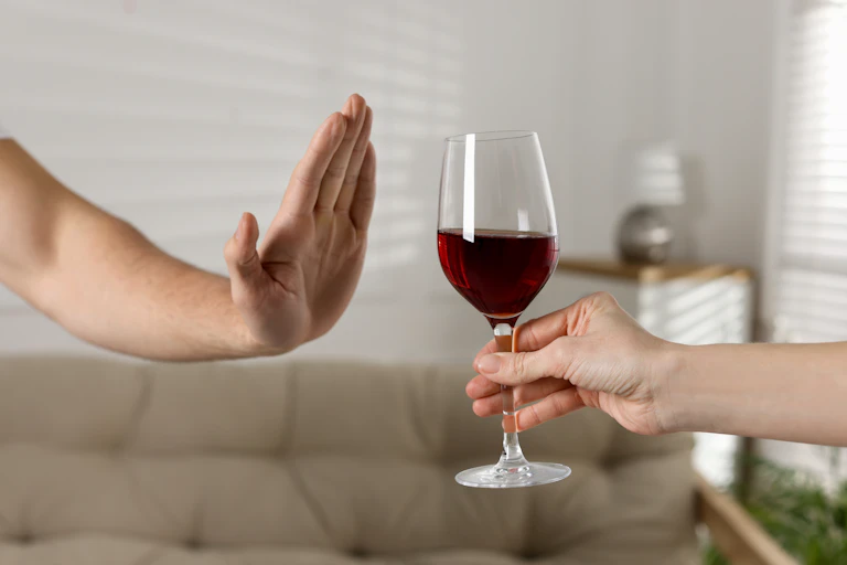 Una mano rechaza una copa de vino tinto