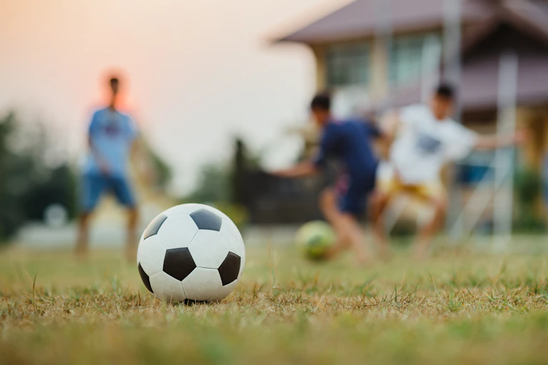 Un ballon de soccer, avec trois joueurs en arrière-plan